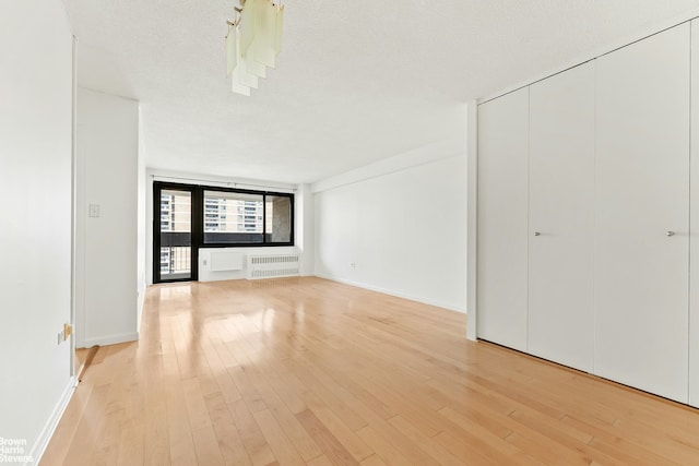 77 Fulton St Unit 9N, New York City, NY 10038 - empty room featuring light wood-style floors and radiator heating unit