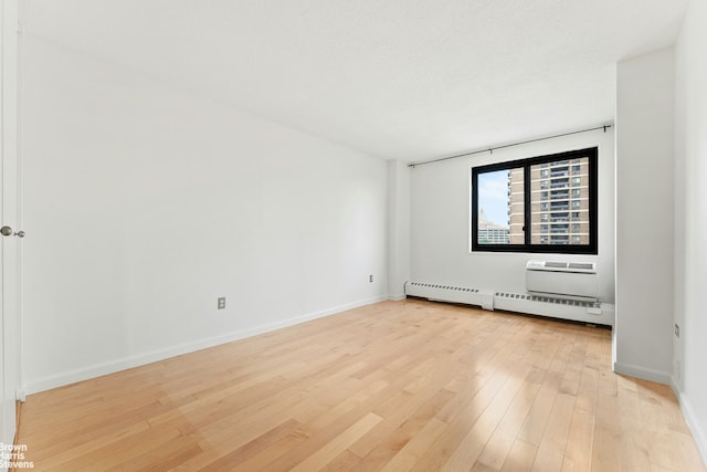 77 Fulton St Unit 9N, New York City, NY 10038 - unfurnished room with baseboard heating, light wood-style floors, and an AC wall unit