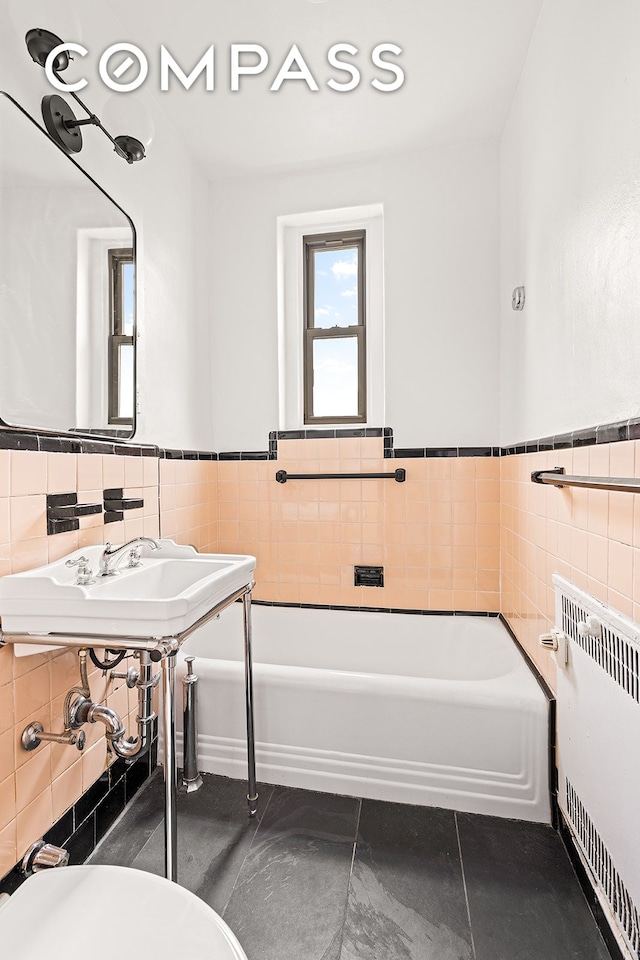 145 Hicks St Unit A55, New York City, NY 11201 - bathroom with tile walls, radiator, a garden tub, and a wainscoted wall