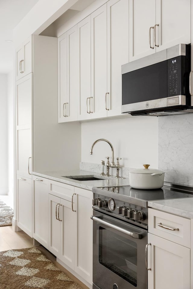 186 Clinton St Unit 4B, New York City, NY 11201 - kitchen with appliances with stainless steel finishes, white cabinetry, and light stone countertops