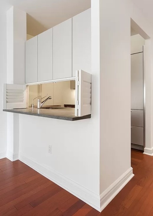 100 Riverside Blvd Unit 7-T, New York City, NY 10069 - kitchen featuring dark wood finished floors, dark countertops, white cabinetry, and a peninsula
