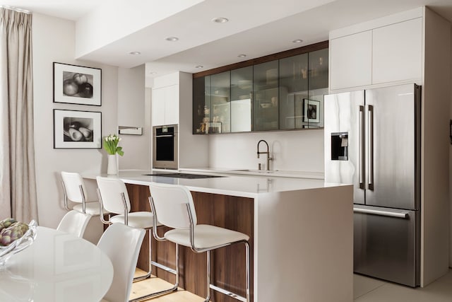45 Sutton Pl S Unit 8H, New York City, NY 10022 - kitchen featuring stainless steel appliances, modern cabinets, a breakfast bar area, light countertops, and recessed lighting