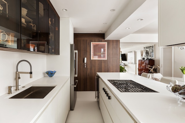 45 Sutton Pl S Unit 8H, New York City, NY 10022 - kitchen featuring black gas cooktop, high end refrigerator, white cabinetry, light countertops, and glass insert cabinets