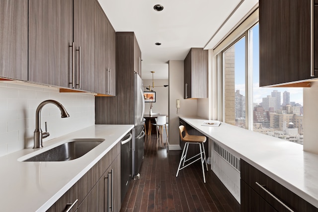 300 E 74th St Unit 23G, New York City, NY 10021 - kitchen featuring modern cabinets, light countertops, backsplash, dark wood-type flooring, and appliances with stainless steel finishes