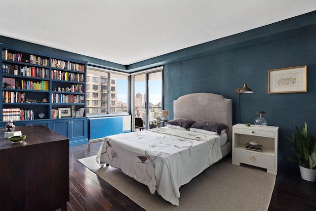 300 E 74th St Unit 23G, New York City, NY 10021 - bedroom featuring dark wood-style flooring, a city view, and wallpapered walls