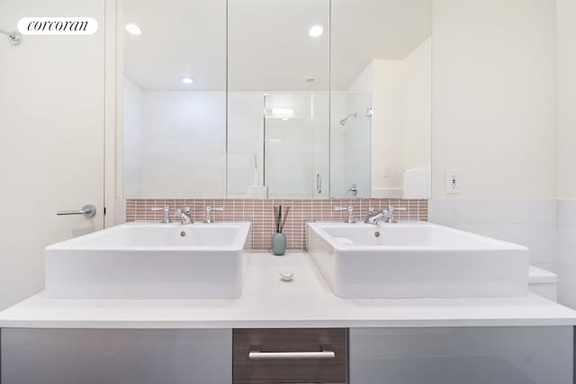 125 W 22nd St Unit 9B, New York City, NY 10011 - bathroom featuring double vanity, a shower with door, and tasteful backsplash