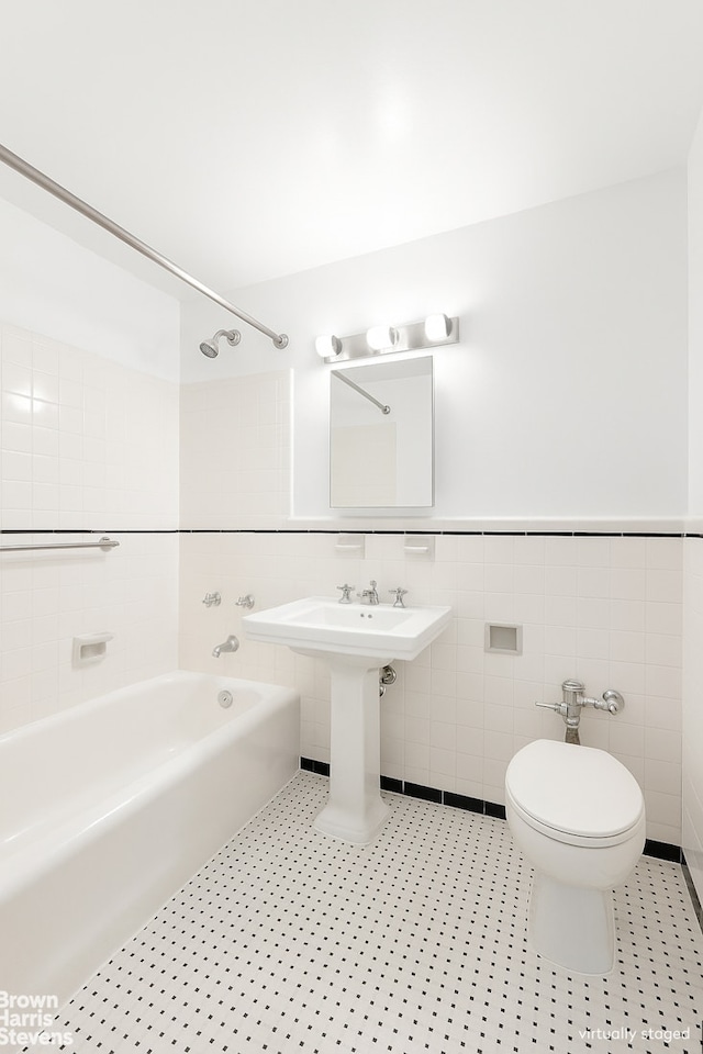 433 E 51st St Unit 11E, New York City, NY 10022 - bathroom featuring tub / shower combination, tile walls, and wainscoting