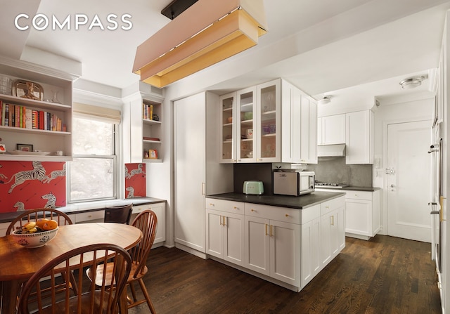 163 E 81st St Unit 3A, New York City, NY 10028 - kitchen featuring dark countertops, white cabinetry, open shelves, dark wood-type flooring, and glass insert cabinets