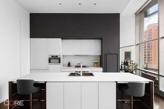 1 York St Unit 6E, New York City, NY 10013 - kitchen featuring modern cabinets, light countertops, white cabinets, a center island with sink, and a breakfast bar