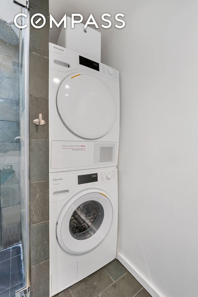 415 W 55th St Unit 4D, New York City, NY 10019 - laundry room with stacked washer and clothes dryer and dark tile patterned flooring