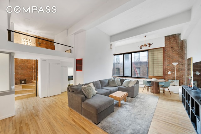 415 W 55th St Unit 4D, New York City, NY 10019 - living room with a fireplace, a towering ceiling, hardwood / wood-style flooring, a chandelier, and brick wall