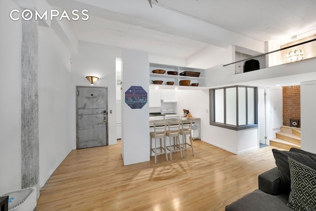 415 W 55th St Unit 4D, New York City, NY 10019 - kitchen with white range, light wood-style floors, white cabinetry, open floor plan, and a high ceiling