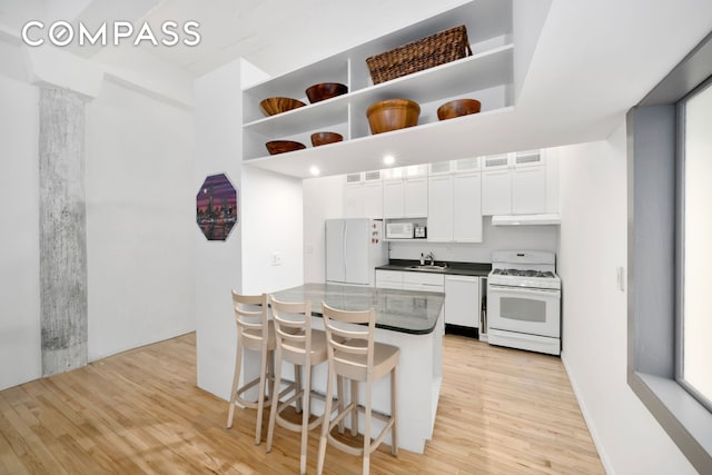 415 W 55th St Unit 4D, New York City, NY 10019 - kitchen with white appliances, light wood finished floors, a kitchen breakfast bar, and white cabinets
