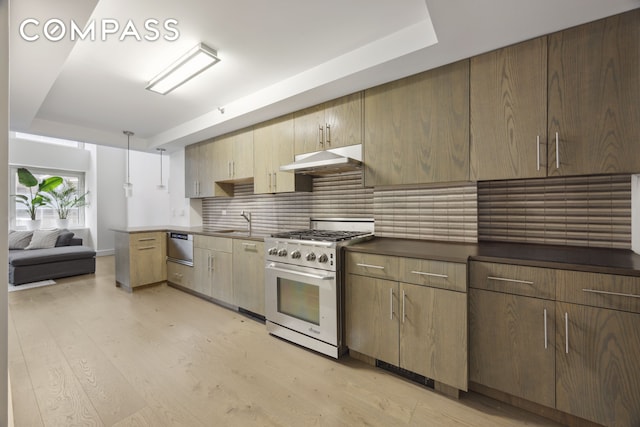 67 Liberty St Unit 10, New York City, NY 10005 - kitchen featuring stainless steel stove, under cabinet range hood, decorative backsplash, and light wood-style flooring