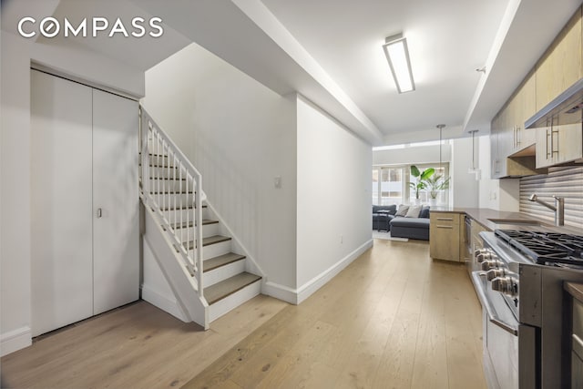 67 Liberty St Unit 10, New York City, NY 10005 - kitchen with high end stainless steel range oven, light wood-style flooring, modern cabinets, open floor plan, and dark countertops