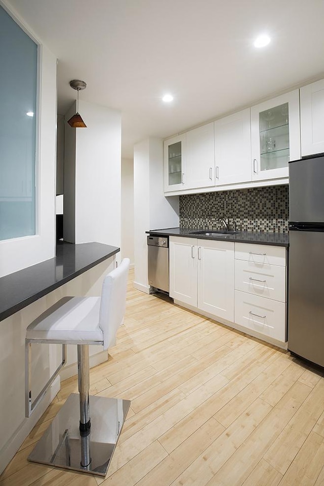 150 W 51st St Unit 1623, New York City, NY 10019 - kitchen featuring appliances with stainless steel finishes, dark countertops, tasteful backsplash, white cabinets, and recessed lighting