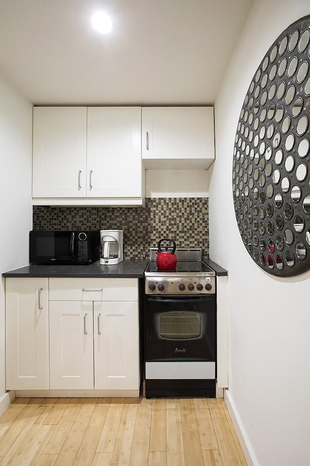 150 W 51st St Unit 1623, New York City, NY 10019 - kitchen with electric range oven, black microwave, dark countertops, and backsplash