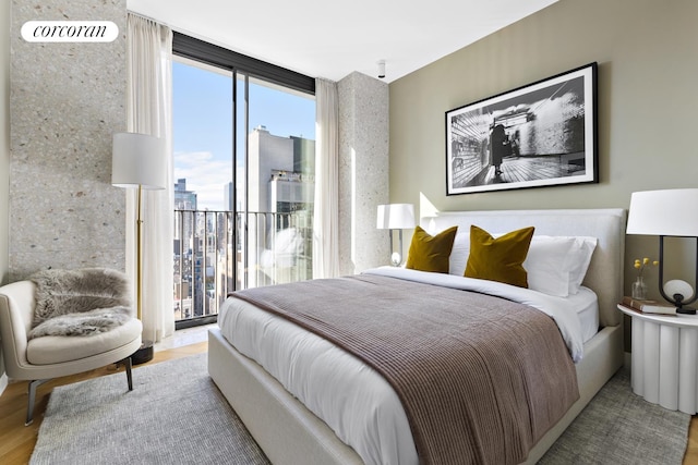 16 W 40th St Unit 25B, New York City, NY 10018 - bedroom featuring access to exterior, expansive windows, wood finished floors, and a city view