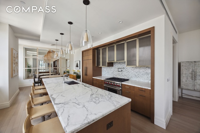 100 Barclay St Unit 15B, New York City, NY 10007 - kitchen with high end stove, decorative backsplash, light wood finished floors, and brown cabinetry