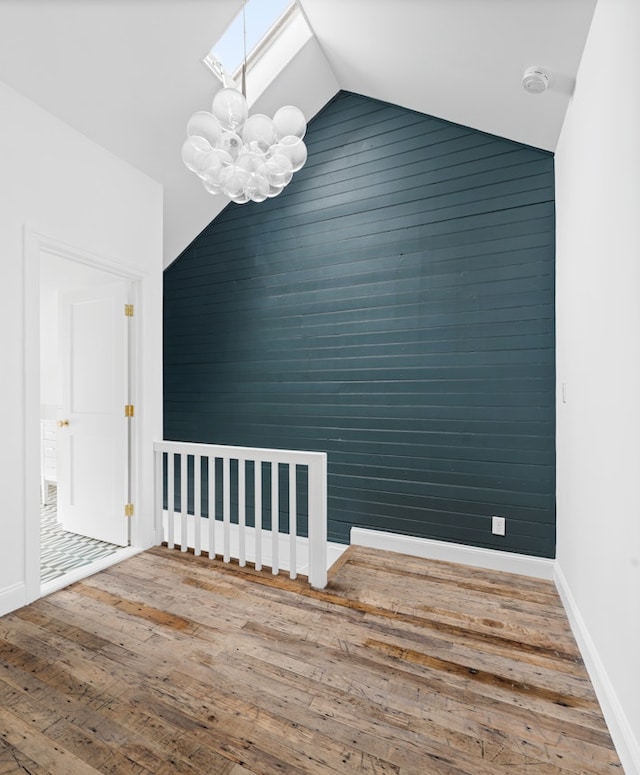 211 Powers St, New York City, NY 11211 - unfurnished dining area with a skylight, an accent wall, wood finished floors, a chandelier, and lofted ceiling