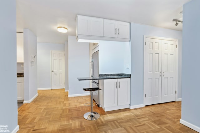 160 E 27th St Unit 11E, New York City, NY 10016 - kitchen with white cabinets, a kitchen bar, and stainless steel fridge