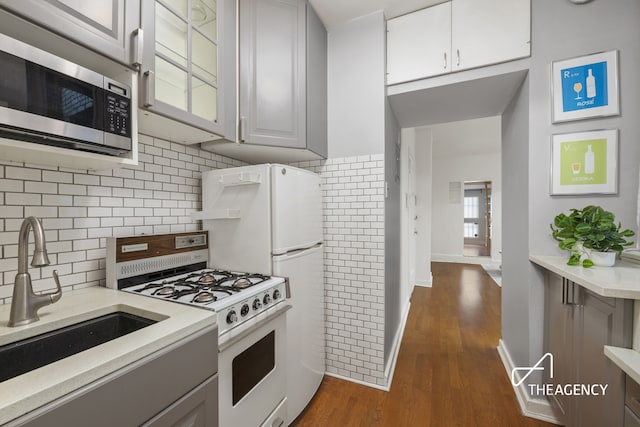 138 E 36th St Unit 1B, New York City, NY 10016 - kitchen with white appliances, light countertops, dark wood finished floors, gray cabinetry, and backsplash