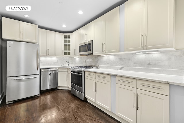 555 Lenox Ave Unit 1A, New York City, NY 10037 - kitchen featuring stainless steel appliances, tasteful backsplash, dark wood-style flooring, glass insert cabinets, and light stone countertops