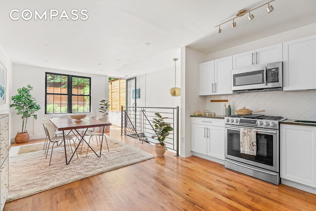 120 Pulaski St Unit 1B, New York City, NY 11206 - kitchen with appliances with stainless steel finishes, light wood-type flooring, backsplash, dark countertops, and white cabinets