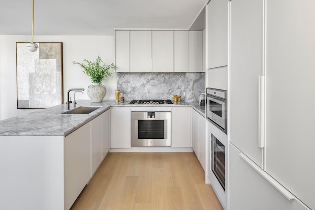 250 E 25th St Ph-A, Ph-A New York City, NY 10010 - kitchen with stainless steel appliances, a peninsula, white cabinetry, light stone counters, and light wood-style floors
