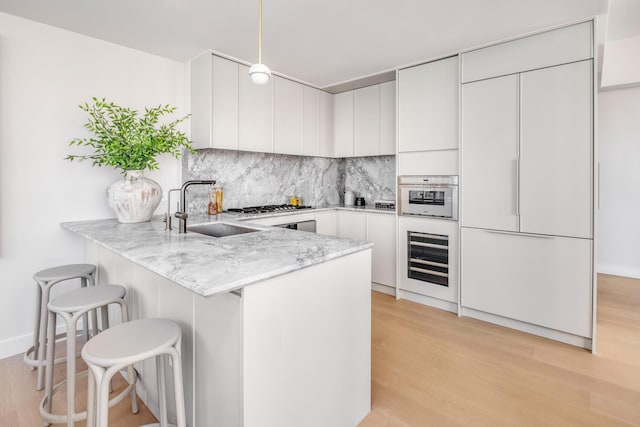250 E 25th St Ph-A, Ph-A New York City, NY 10010 - kitchen featuring wine cooler, paneled built in fridge, a peninsula, light wood-type flooring, and backsplash