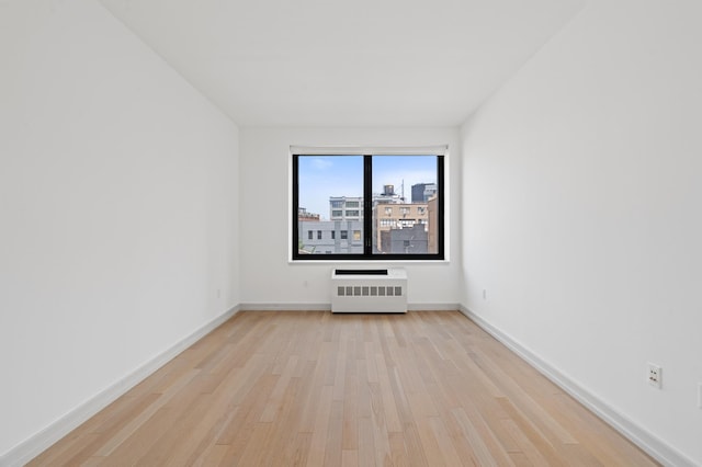 21-45 44th Dr Unit 4-C, New York City, NY 11101 - unfurnished room featuring light wood finished floors, a wall unit AC, and a city view