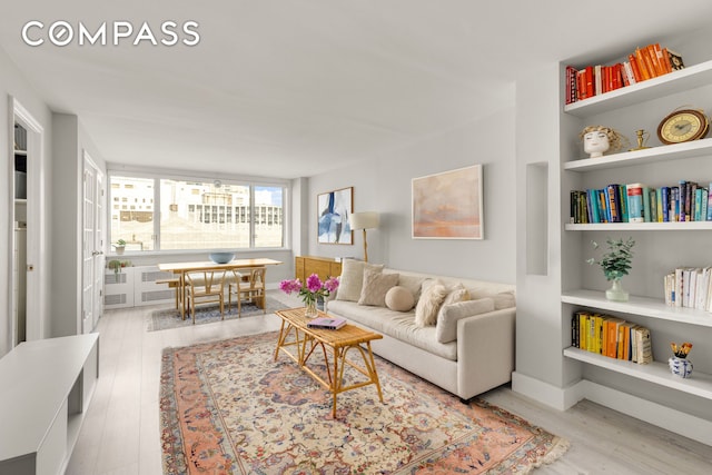 333 E 14th St Unit 11A, New York City, NY 10003 - living area with wood finished floors, built in shelves, and radiator heating unit