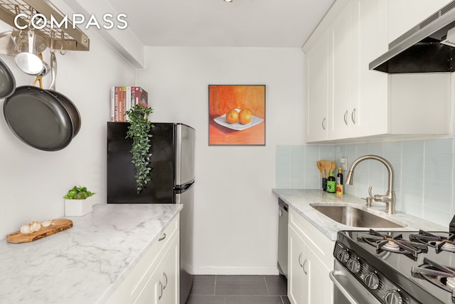 333 E 14th St Unit 11A, New York City, NY 10003 - kitchen featuring under cabinet range hood, appliances with stainless steel finishes, decorative backsplash, light stone countertops, and white cabinets