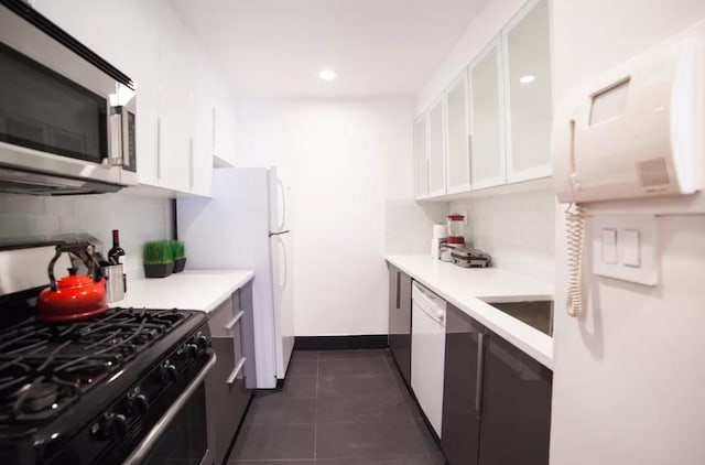 179 Grand St Unit 2-F, New York City, NY 10013 - kitchen featuring white appliances, tasteful backsplash, white cabinetry, light countertops, and dark tile patterned flooring
