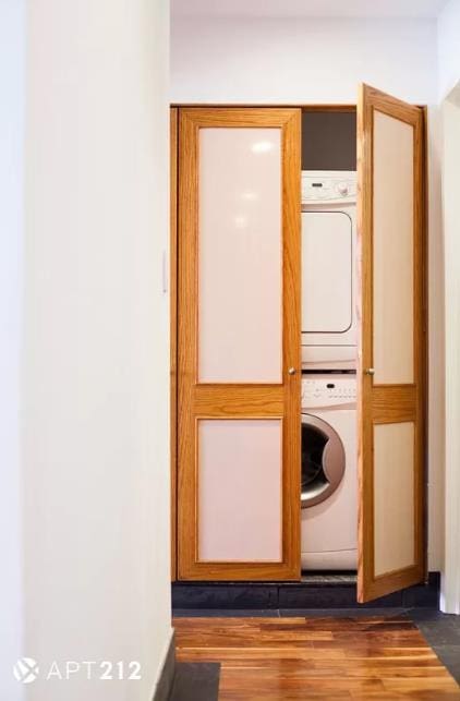 179 Grand St Unit 2-F, New York City, NY 10013 - washroom featuring estacked washer and dryer and dark wood-type flooring