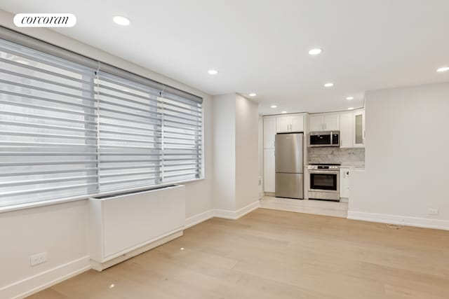 200 E 24th St Unit 301, New York City, NY 10010 - kitchen with appliances with stainless steel finishes, white cabinetry, light wood-type flooring, tasteful backsplash, and glass insert cabinets