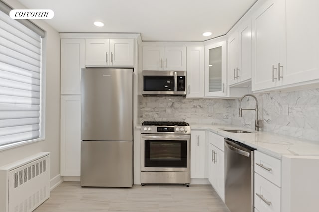200 E 24th St Unit 301, New York City, NY 10010 - kitchen with appliances with stainless steel finishes, radiator, plenty of natural light, light stone counters, and recessed lighting