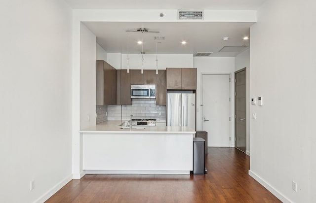 27-17 42nd Rd Unit 14-B, New York City, NY 11101 - kitchen with appliances with stainless steel finishes, light countertops, tasteful backsplash, dark wood-type flooring, and a peninsula