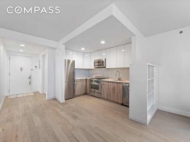 557 Hart St Unit 3A, New York City, NY 11221 - kitchen with stainless steel appliances, light countertops, light wood-style floors, white cabinetry, and recessed lighting