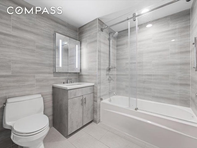 557 Hart St Unit 3A, New York City, NY 11221 - full bathroom with bath / shower combo with glass door, vanity, tile patterned flooring, and tile walls