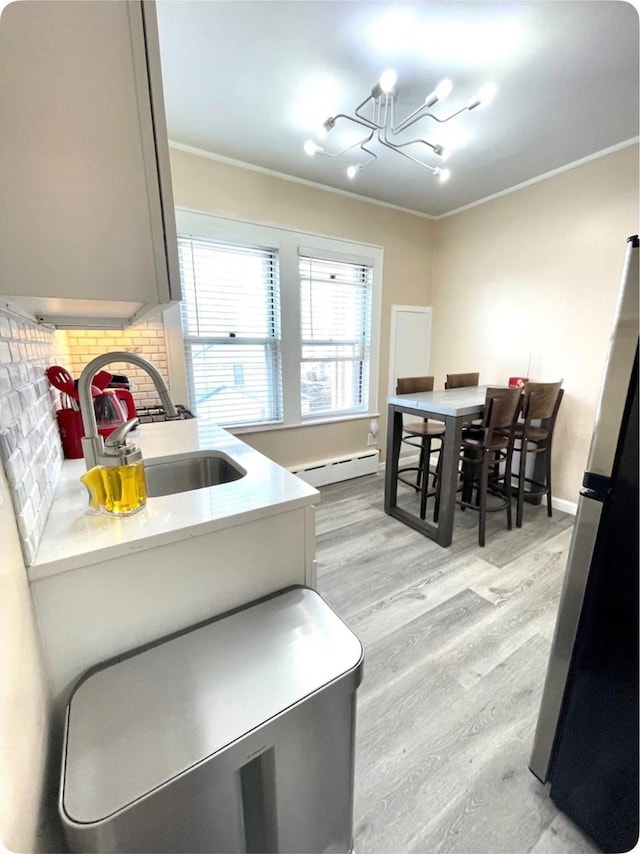 100-15 Ascan Ave, New York City, NY 11375 - kitchen with a baseboard radiator, a chandelier, light countertops, light wood-style floors, and crown molding