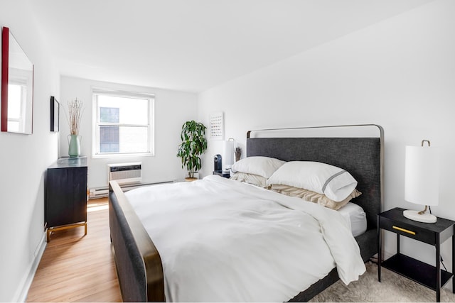 708 Washington St Unit 5B, New York City, NY 10014 - bedroom with light wood-type flooring, a wall unit AC, and a baseboard radiator