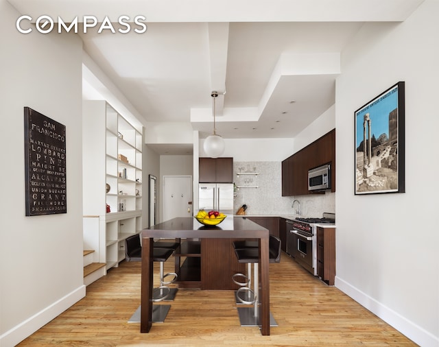 21 E 22nd St Unit 7F, New York City, NY 10010 - kitchen with premium appliances, dark brown cabinets, a breakfast bar, and light wood-style floors