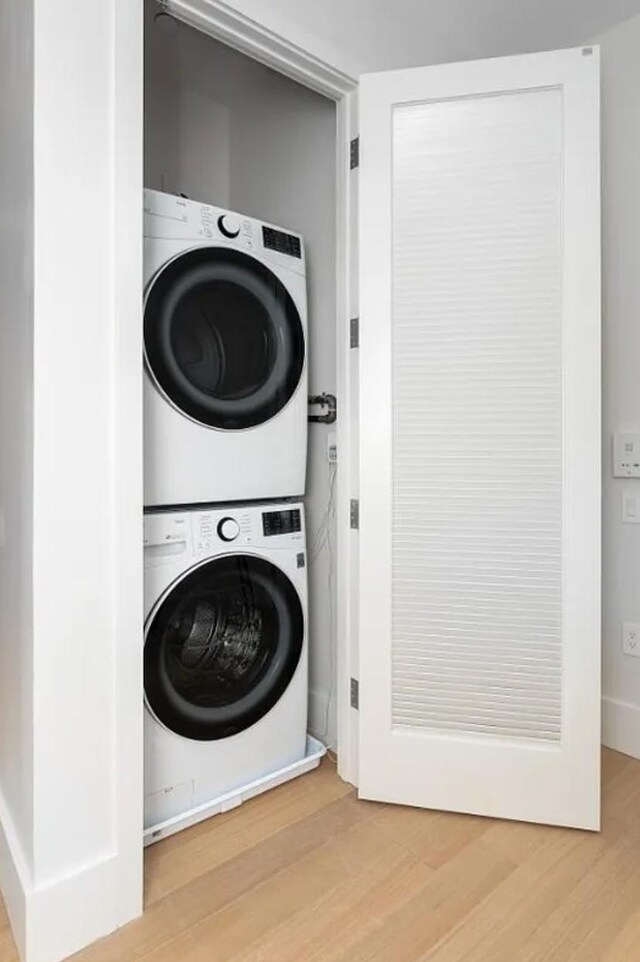 517 W 29th St Unit 8B, New York City, NY 10001 - laundry area featuring stacked washing machine and dryer and wood finished floors