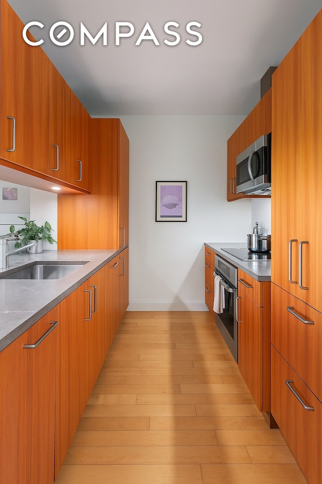 450 E 83rd St Unit 5F, New York City, NY 10028 - kitchen with stainless steel appliances, modern cabinets, brown cabinetry, and light wood finished floors