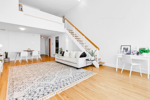 121 W 19th St Unit 3D, New York City, NY 10011 - living room with stairway, wood-type flooring, and a towering ceiling