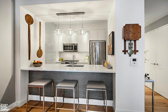 23 W 116th St Unit 4H, New York City, NY 10026 - kitchen with stainless steel appliances, a peninsula, a breakfast bar, and wood finished floors