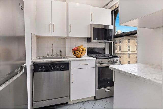 235 W End Ave Unit 16A, New York City, NY 10023 - kitchen featuring stainless steel appliances, white cabinets, decorative backsplash, and light tile patterned flooring