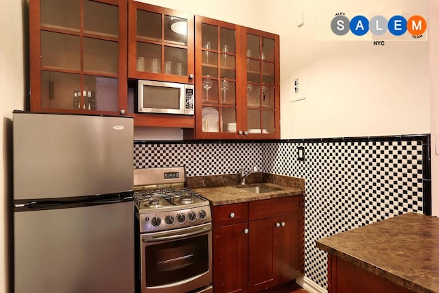 134 W 82nd St Unit 2C, New York City, NY 10024 - kitchen featuring appliances with stainless steel finishes, dark countertops, glass insert cabinets, backsplash, and wainscoting