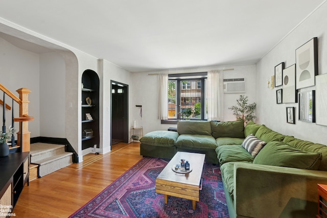 31-28 56th St, New York City, NY 11377 - living area featuring stairs, wood finished floors, a wall mounted air conditioner, and built in shelves